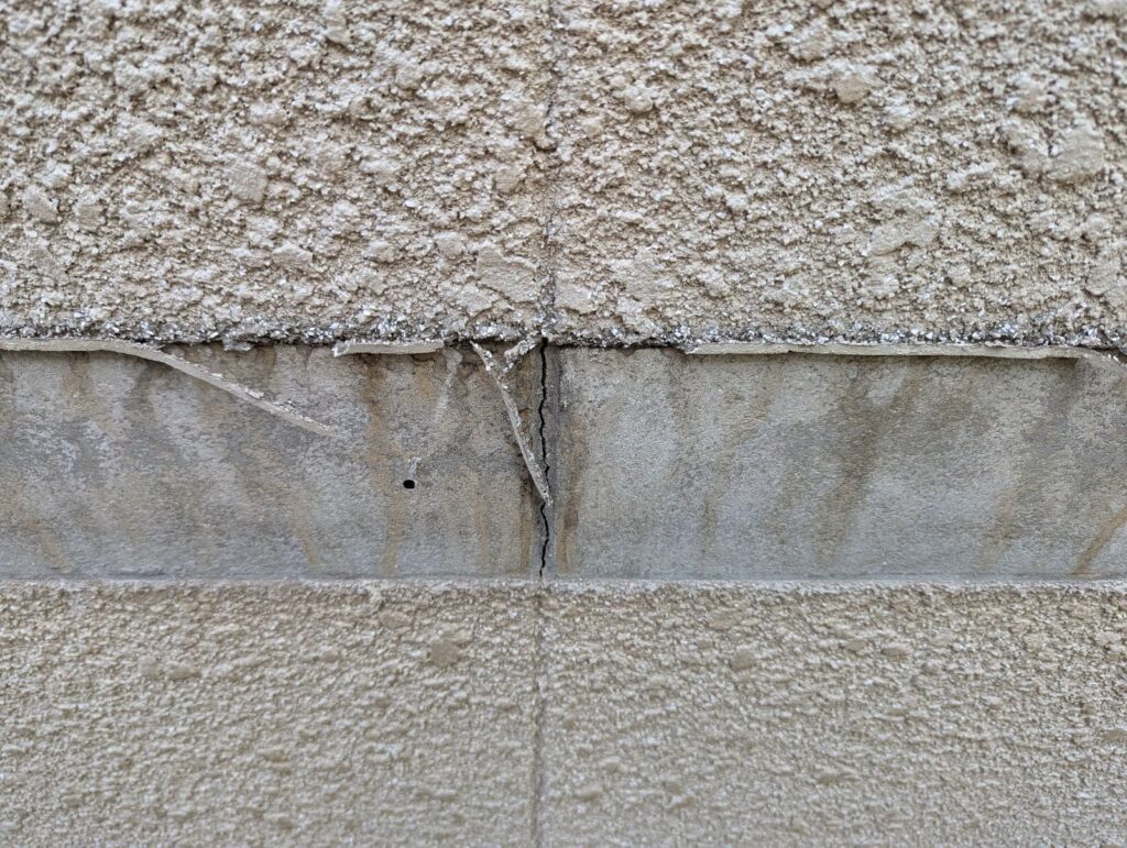 劣化した幕板下のひび割れているモルタル外壁